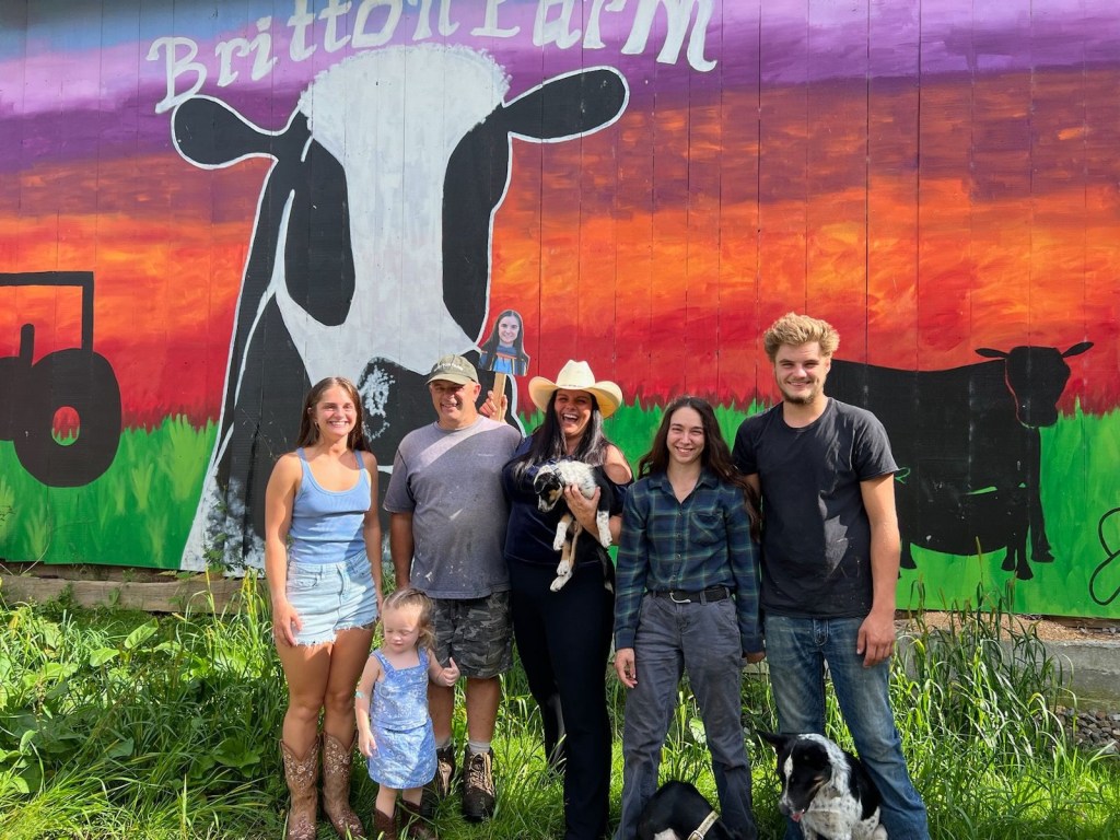 Larry and Josie Britton are shown with their family in front of the colorful mural on their barn at their farm on Watkins Hill Road.